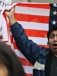 SAN FRANCISCO - MARCH 24: A protestor carries an American flag during an immigration reform demonstration March 24, 2010 in San Francisco, California. More than 2,000 protestors staged a demonstration outside of U.S. Sen. Dianne Feinstein's (D-CA) office calling on the U.S. Senate to fix the broken immigration system. (Photo by Justin Sullivan/Getty Images)