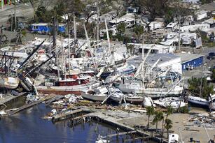 In this aerial photo, damaged boats and debris are stacked along the shore in the aftermath of Hurricane Ian, Thursday, Sept. 29, 2022, in Fort Myers, Fla. (AP Photo/Wilfredo Lee)